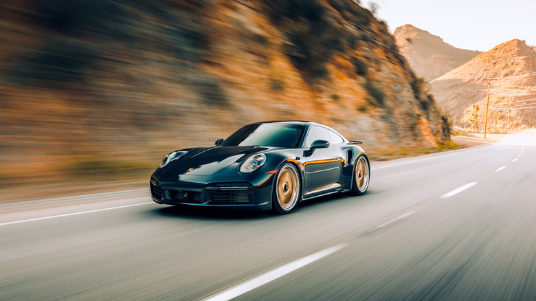 Black car cruising along hills with blurred background