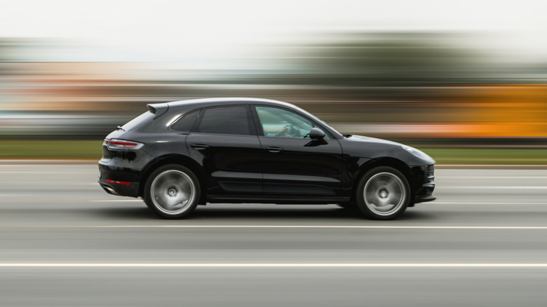 A car speeding down the highway with blurred trees in the background