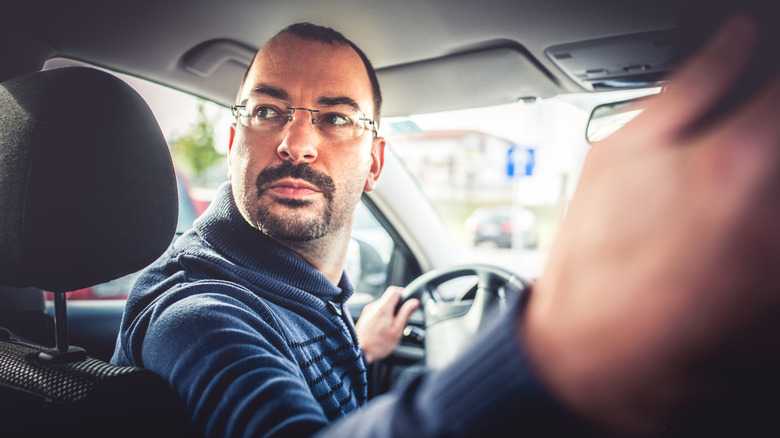 Man looking backwards while reversing in a car