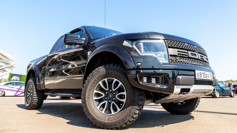 Ford Raptor with large tires turned in, low-shot of front-right 3/4