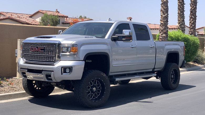 Lifted GMC Sierra Denali parked roadside, front-left 3/4 view