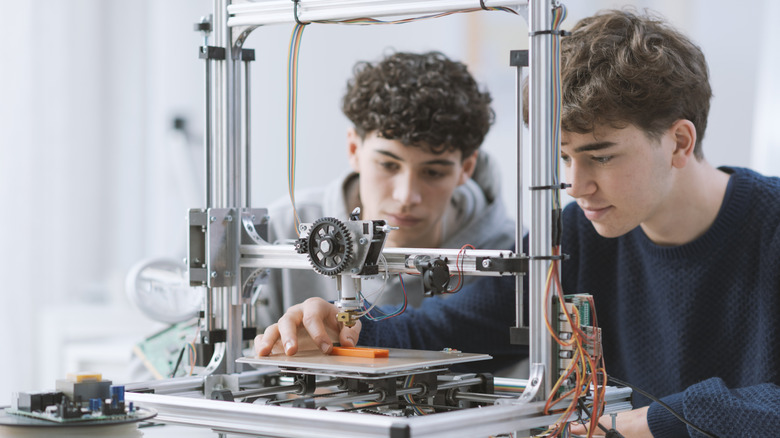 Two young men working with a 3D printer