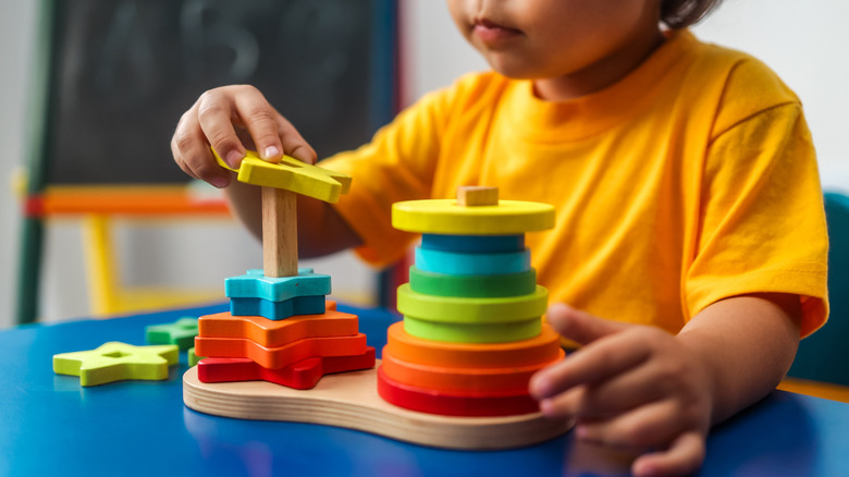 A young child playing with a ring puzzle toy