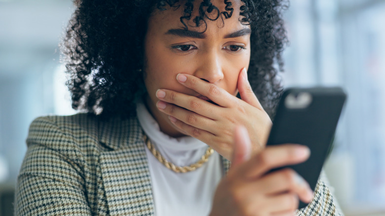 A businesswomen with an expression of shock seeing her phone