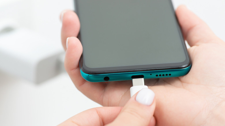 person plugging a cable into a smartphone