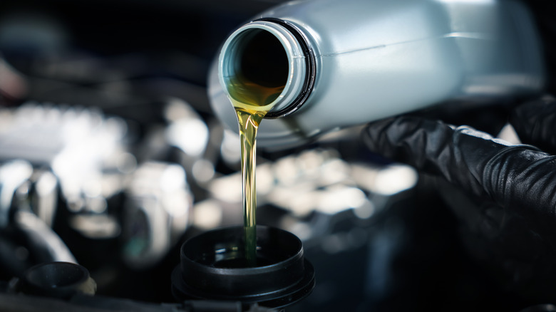 A person pouring motor oil into a car