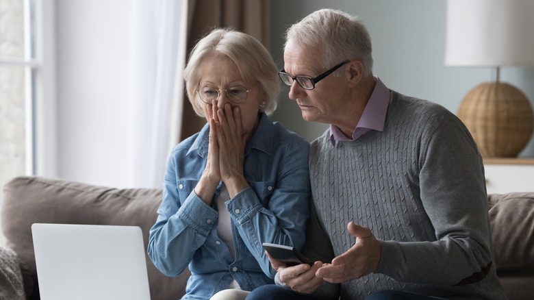 Elderly couple looking shocked at what they see on a computer screen