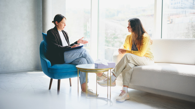 woman talking to female therapist beside bright window