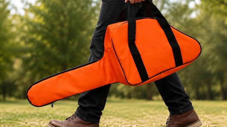 A person carrying a chainsaw in an orange bag.