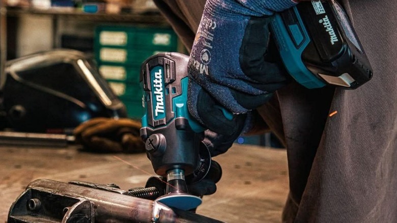 Makita 18V grinder being used on pipe