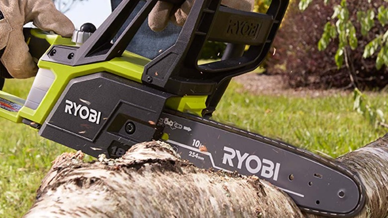 A person cutting wood with a Ryobi chainsaw.