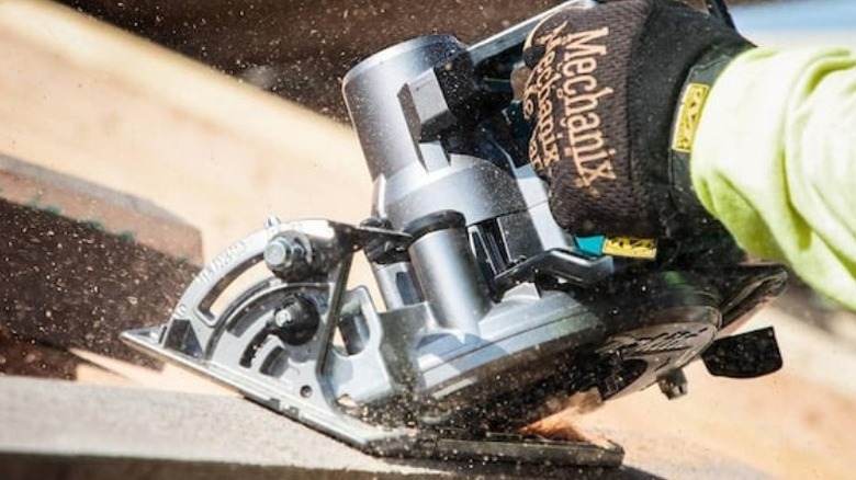 Person cutting beam with Makita rear handle circular saw