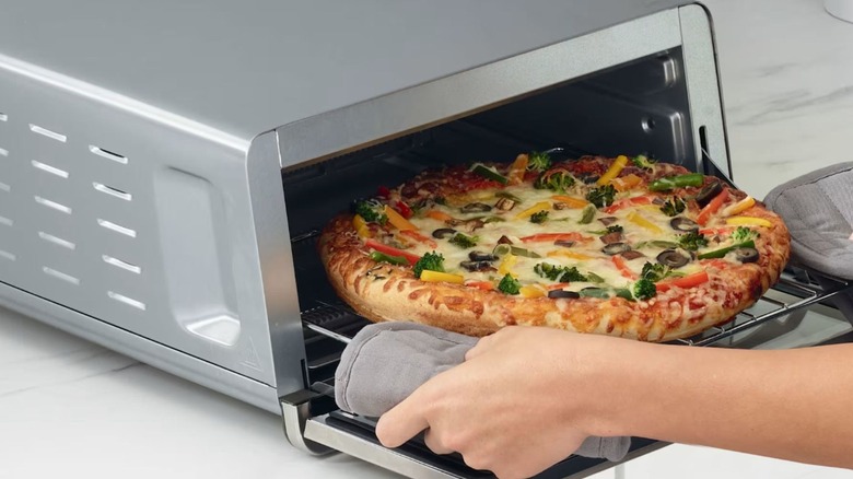 Person taking pizza out of Ninja Flip Toaster Oven