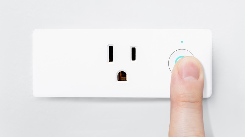 a person turning on a smart plug
