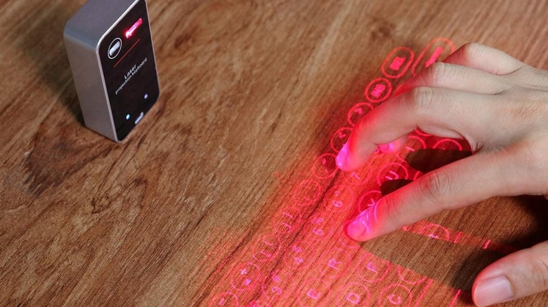 A person typing on a wooden surface using a virtual laser keyboard