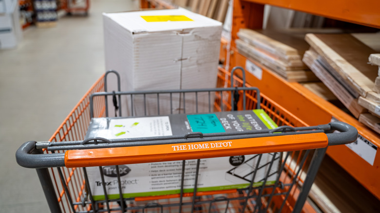 A hand holding up a cell phone with a white screen with blurred store aisles in the background