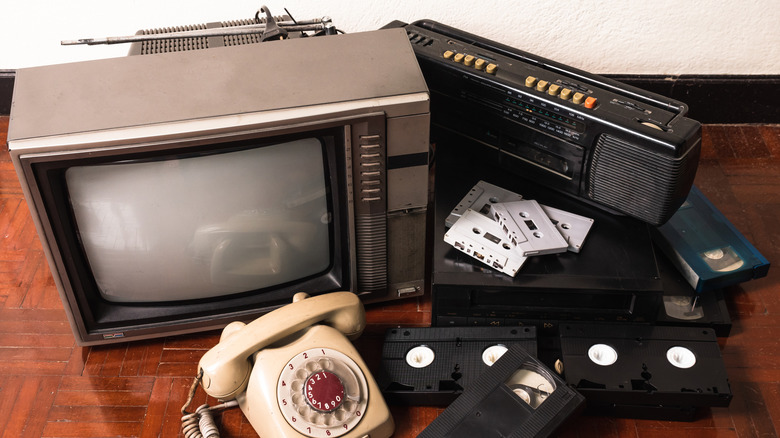A retro TV, telephone, boombox, cassette tapes, and VHS tapes