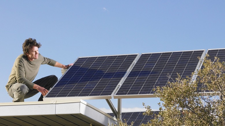 man inspecting rooftop solar panels