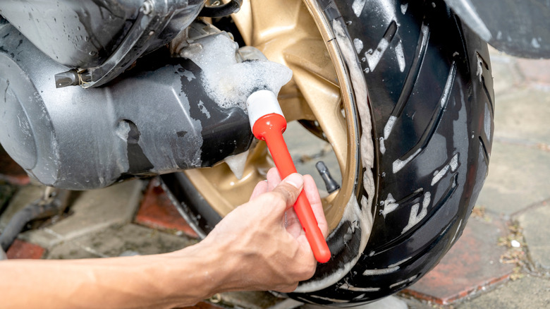 A cleaning professional using a brush to clean a motorcycle tire
