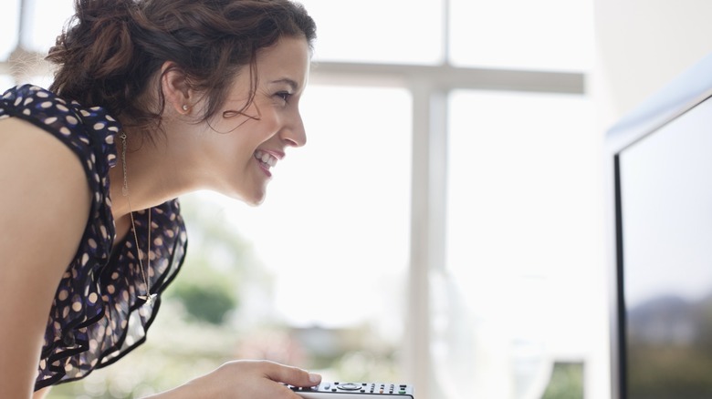 Woman smiling as she points remote at tv