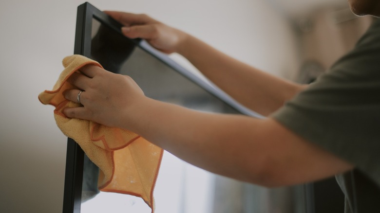 Close up of person cleaning tv with cloth