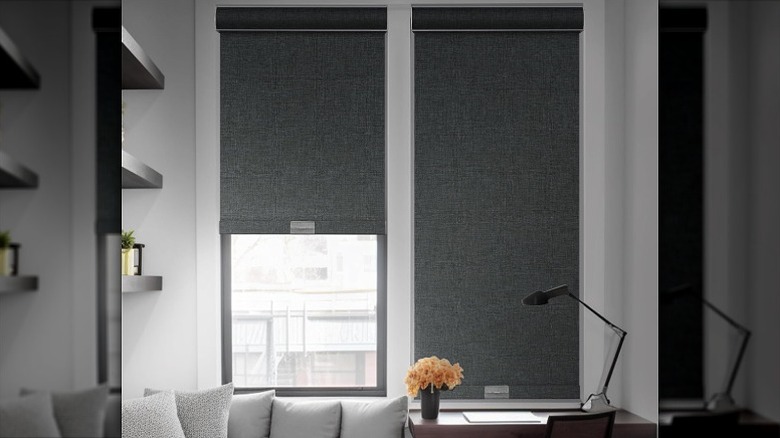 Grey blackout roller shades over vertical windows