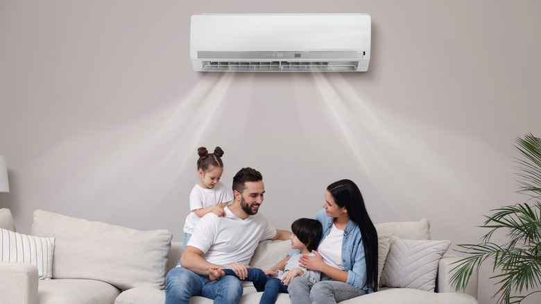 A family sitting happily on a sofa with the AC working