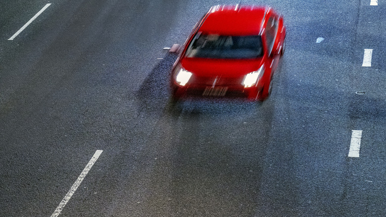 Small red car traveling quickly down a road