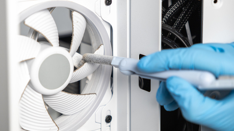 Gloved hand cleaning dusty PC case fan