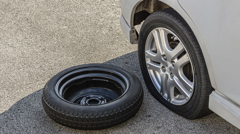 Close up of a car with a flat tire and its spare tire.