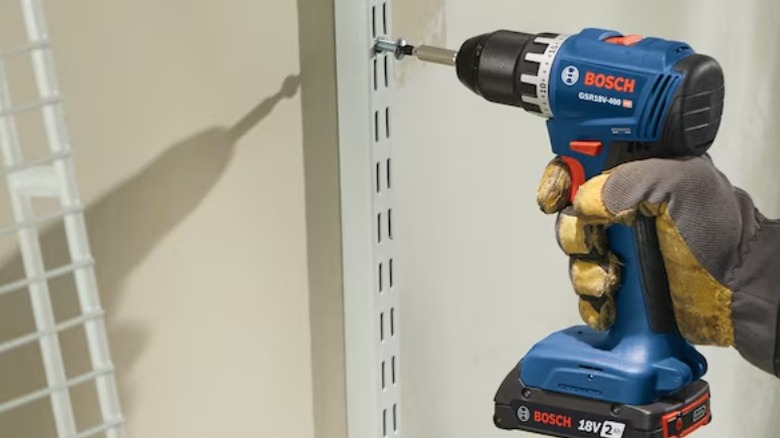 Person using Bosch 18V ½-inch Keyless Brushless Drill on rack