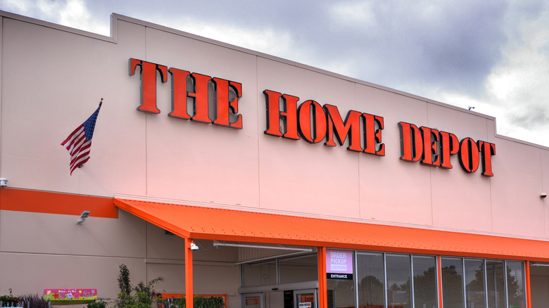 A Home Depot front sign and entrance with a blue sky above