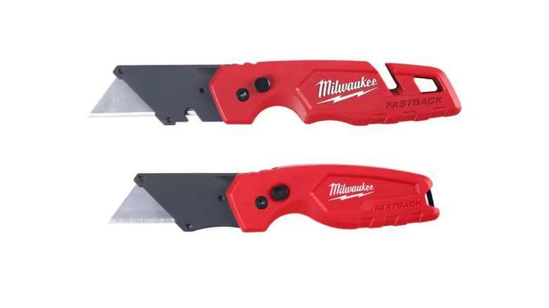 Red and black folding utility knife with blades out on a white background