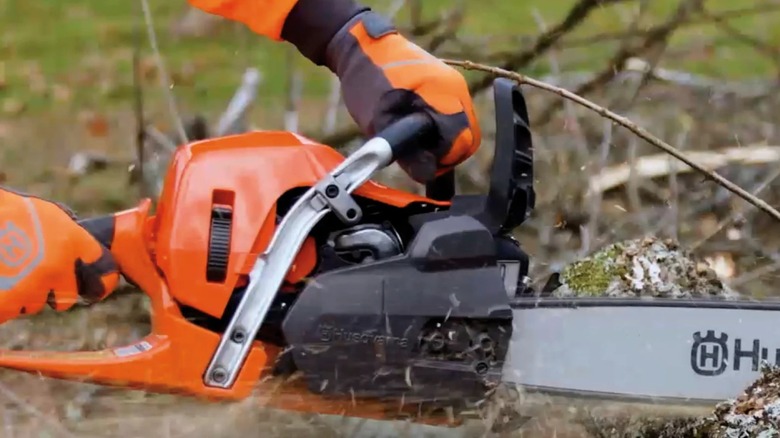 A person using a Husqvarna chainsaw on a tree.