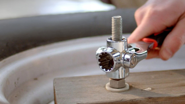 A 48-in-1 ratchet loosening a nut on a piece of wood