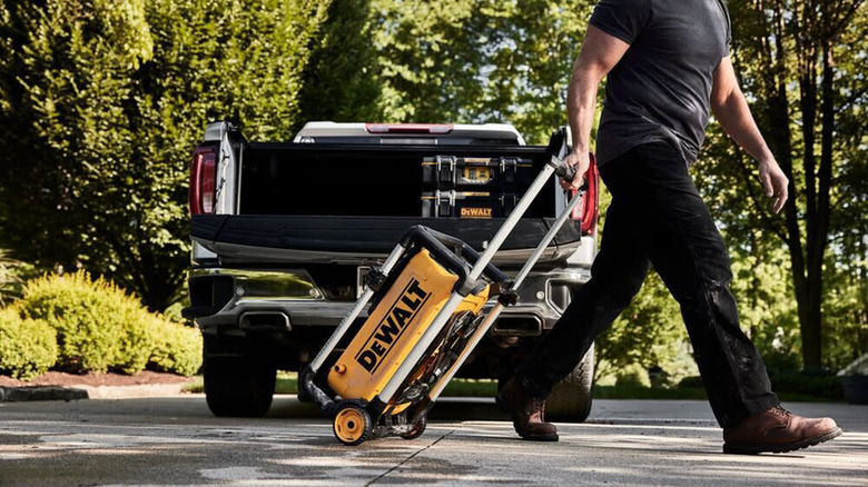 A man pulling a DeWalt power washer across a driveway