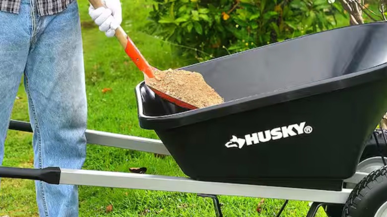 Person shoveling dirt into Husky 6 cu-ft Wheelbarrow