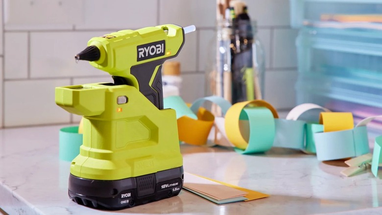 Ryobi 18V One+ Compact Glue Gun on a table with craft supplies in the background
