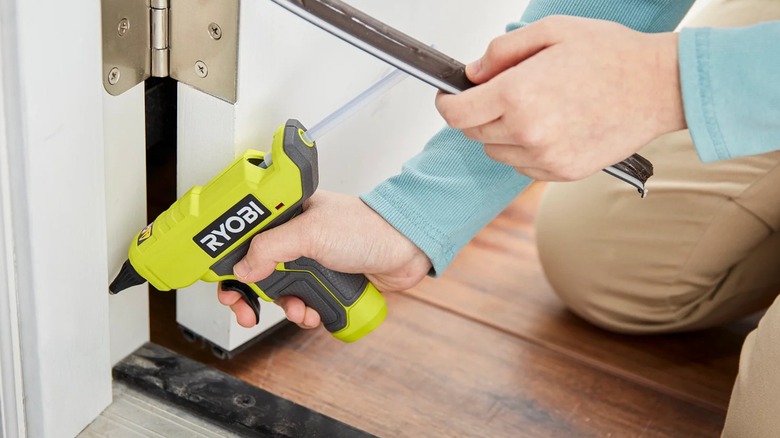 Person using a Ryobi 18V One+ Compact Glue Gun on a doorjamb