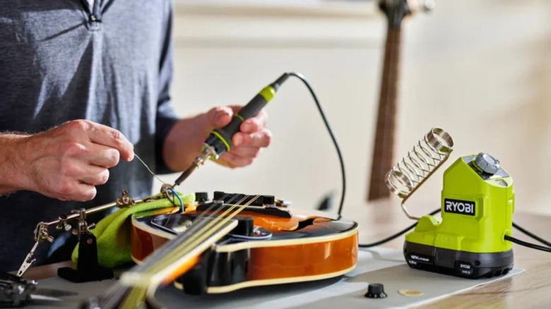 Person using a Ryobi 18V One+ 120W Soldering Iron on a mandolin
