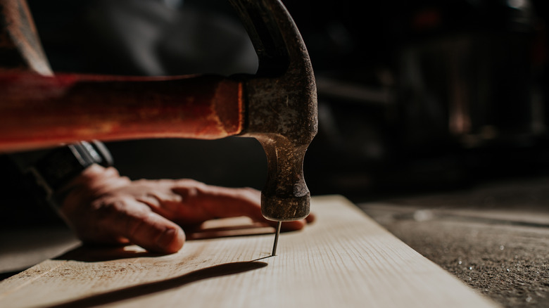 hammering a nail into a board