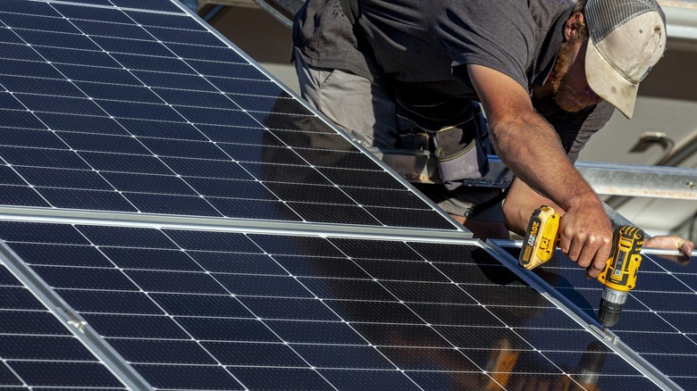 Man screwing solar panel to roof