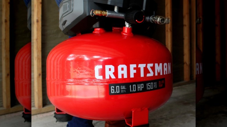 Person carrying a Craftsman Portable Electric 6-Gallon 150 PSI Pancake Air Compressor at a job site