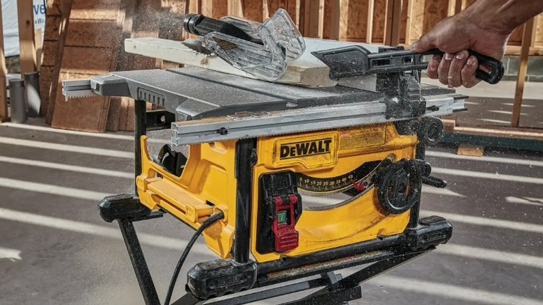 Person cutting board on DeWalt 8 ¼-inch 15 Amp Portable Jobsite Table Saw