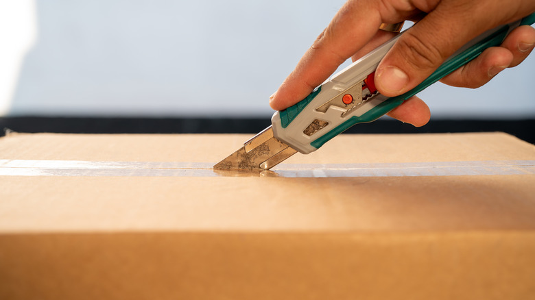person cutting box with knife