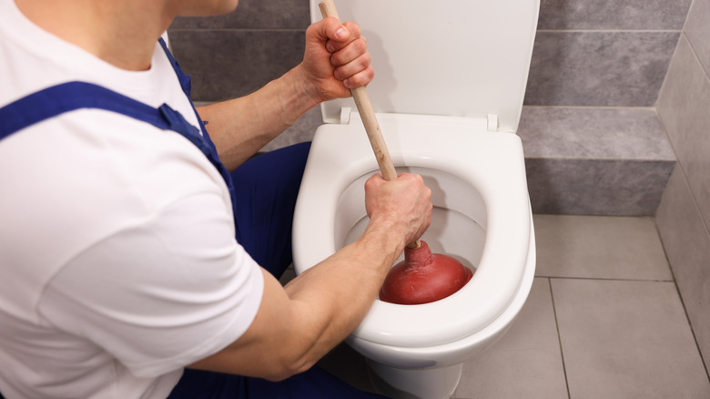 A plumber using the wrong plunger on a toilet