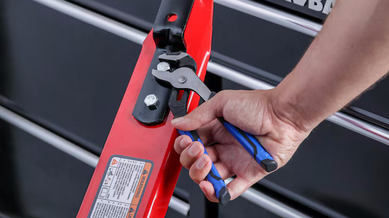 Pair of Kobalt pliers being used on a red bar with a black toolbox background