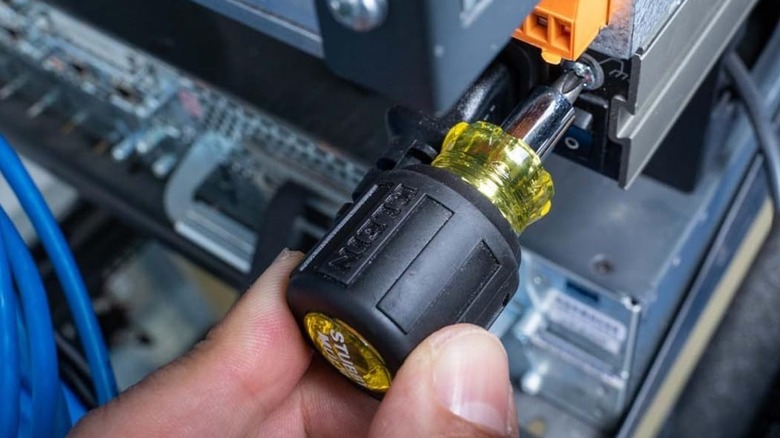 person using stubby screwdriver on electronics