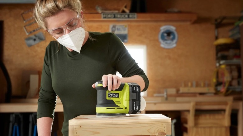 Person removing sanding paper from their Ryobi sander