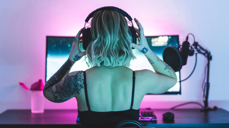 A woman putting on a headset in front of their PC.